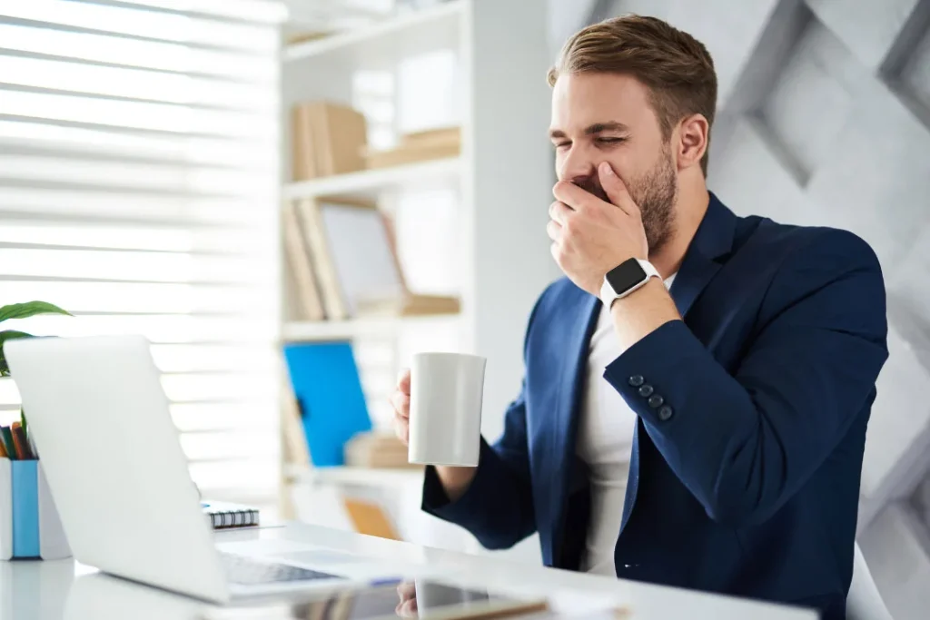 A young man having a cup of tea while working on the laptop.